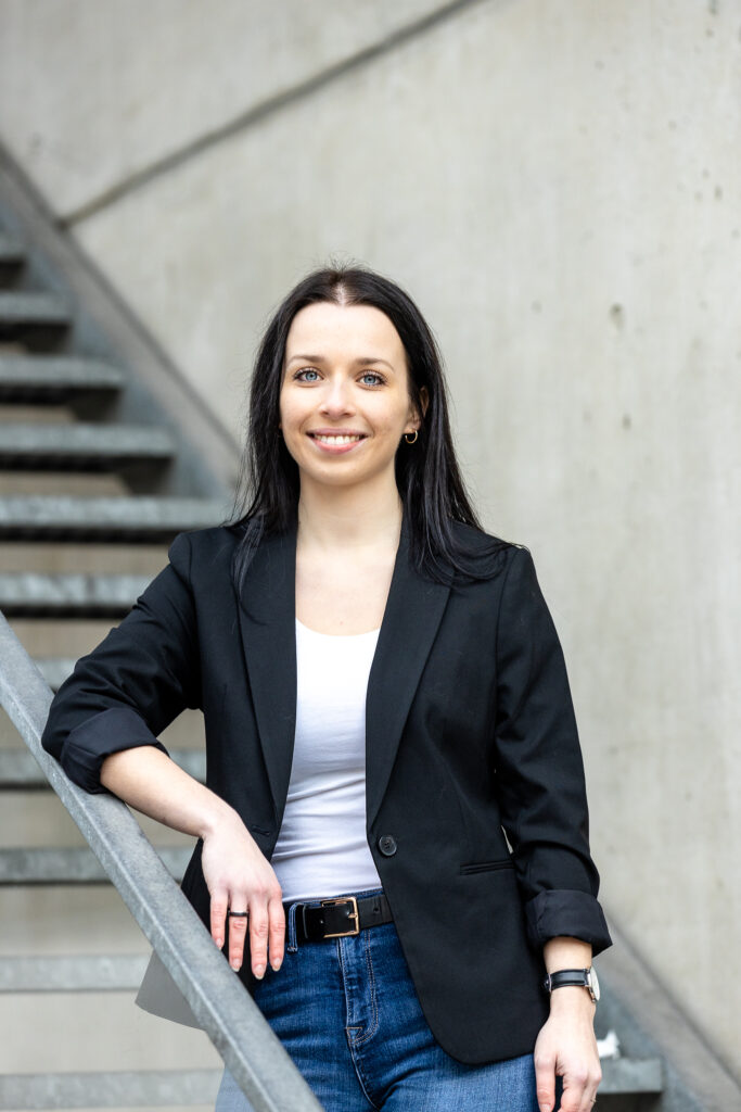 Porträtfoto von Susanne Drescher, Co-Founderin von Bloxxi. Sie hat schulterlanges schwarzes Haar, trägt einen schwarzen Blazer mit weißem Top drunter und lächelt freundlich.